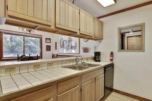 A kitchen with wooden cabinets, a double sink, a coffee maker, and a fire extinguisher. - The Aspens at Olympic Valley (Squaw Valley)
