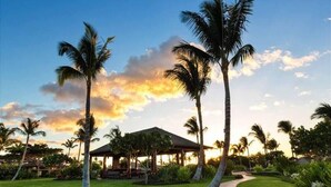 Um resort tropical com palmeiras, um gazebo e um gramado bem cuidado.