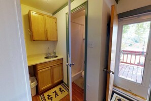 A compact kitchen with wooden cabinets, a sink, and a small window. - Hot Tub, Kokopelli Kabyn, Cute and Cozy! (Blanding)