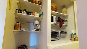 A kitchen with white shelves holding various kitchen items, a coffee maker, a microwave, and a toaster. - Hot Tub, Kokopelli Kabyn, Cute and Cozy! (Blanding)