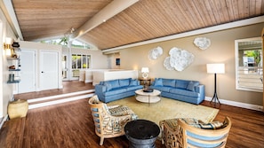 A spacious living room with a blue sectional sofa, a round coffee table, and wicker chairs.