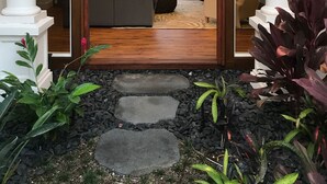 A modern entrance with a glass door leading to a living area with a sofa and a dining table.
