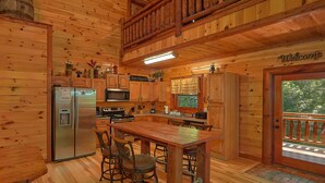Ein Holzblockhaus-Innenraum mit Küche, Essbereich und einem Balkon.
