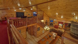Ein Holzblockhaus-Innenraum mit Billardtisch, Kamin, Fernseher und Fahrrad.