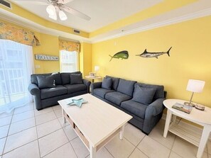 Ein Wohnzimmer mit zwei Sofas, einem Couchtisch, einer Lampe und einer Wand mit Fischmotiven.