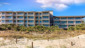 Ett hotell vid stranden med flera balkonger, en sandstrand framför och en klar himmel.