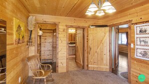 A wooden interior with a wooden ceiling, a chandelier, a chair, a door, and a wall with animal pictures. - W-W: Long View "Safari" Cabin Overlooking Canyon! (Monticello)
