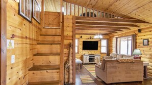 A wooden cabin interior with a staircase, a living room with a sofa, a television, and a dining area. - W-W: Long View "Safari" Cabin Overlooking Canyon! (Monticello)