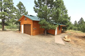 A wooden cabin with a green roof, a garage, and a small porch. - W-W: Long View "Safari" Cabin Overlooking Canyon! (Monticello)