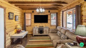 A log cabin interior with a television, sofa, and wooden walls. - W-W: Long View "Safari" Cabin Overlooking Canyon! (Monticello)