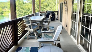 A covered patio with a table and chairs, overlooking a body of water and greenery. - 3 BR, 2 Bath Condo at Vickery Resort &  Table Rock Lake with Dock Access (Hollister)