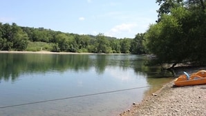 A calm lake with a boat on the shore and a forested hill in the background. - 3 BR, 2 Bath Condo at Vickery Resort &  Table Rock Lake with Dock Access (Hollister)
