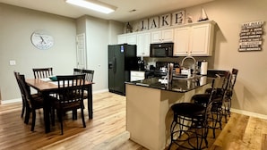 A modern kitchen with white cabinets, a black refrigerator, and a microwave. - 3 BR, 2 Bath Condo at Vickery Resort &  Table Rock Lake with Dock Access (Hollister)