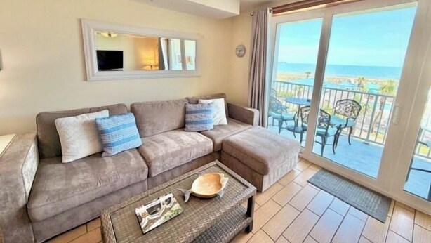 Ein Wohnzimmer mit Sofa, Couchtisch und Meerblick durch eine Schiebetür.