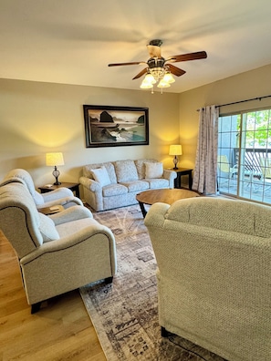 A living room with a sofa, two armchairs, a coffee table, a ceiling fan, a painting, and a view through a window. - 3 BR, 2 Bath Vickery Resort Condo, on Table Rock Lake with Dock Access (Hollister)