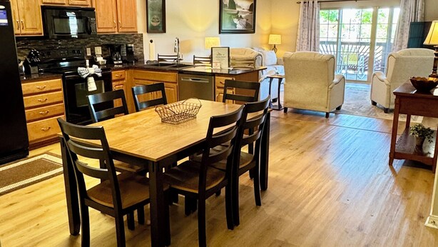 A modern kitchen with wooden cabinets, a dining table with chairs, a refrigerator, and a microwave. - 3 BR 2 Bath Vickery Resort Walk In Condo, on Table Rock Lake with Dock Access (Hollister)