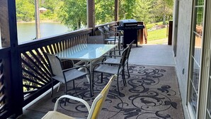 A covered patio with a table and chairs, a grill, and a view of a lake and trees. - 3 BR 2 Bath Vickery Resort Walk In Condo, on Table Rock Lake with Dock Access (Hollister)