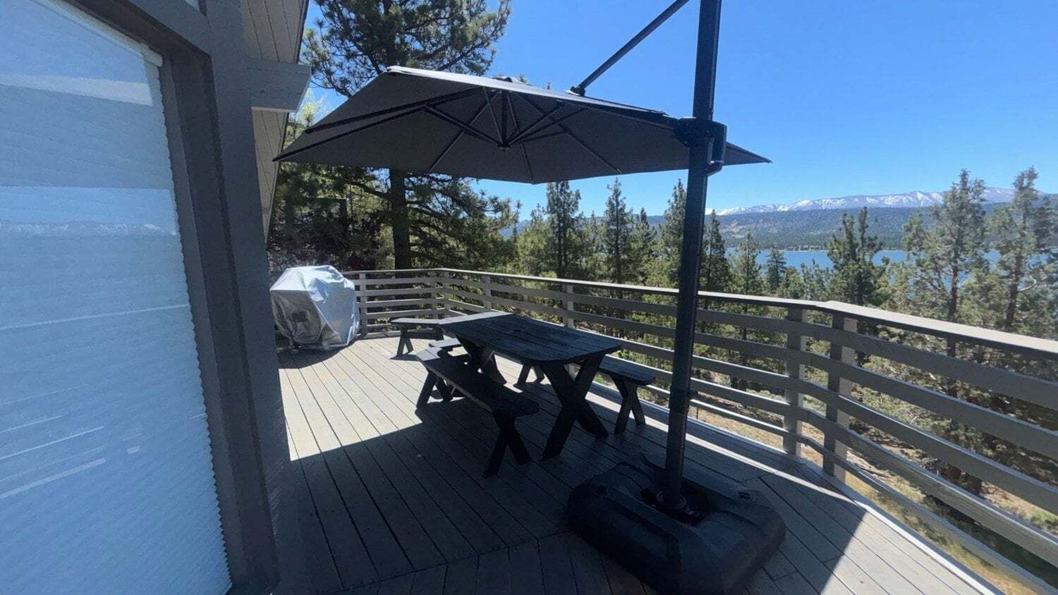 Eine Terrasse mit Picknicktischen und einem Sonnenschirm mit Blick auf eine gebirgige Landschaft.