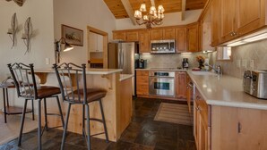 A kitchen with wooden cabinets, stainless steel appliances, and a chandelier.