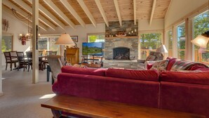 A spacious living room with a stone fireplace, a large TV, and a red sofa.