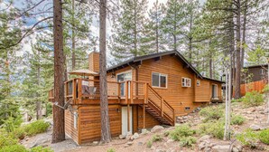 A wooden cabin with a deck, a staircase, and a door.