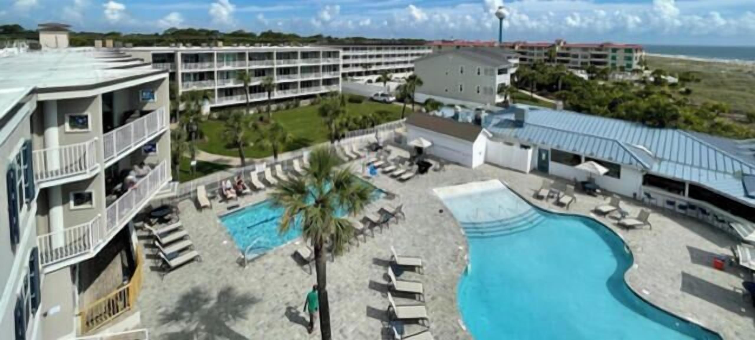 Et hotel med flere balkoner, en swimmingpool og en strand.