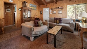 Et hyggeligt interiør i en træhytte med to sofaer, et sofabord og et spisebord.