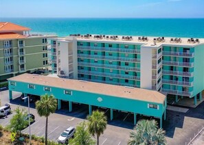 A multi-story hotel with a parking lot and a view of the ocean.