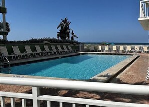 Piscina con sillas de descanso y vistas al océano.
