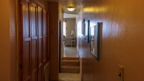 Ein Korridor mit Holztüren, einer Treppe und gerahmten Bildern an der Wand.