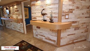 Zona de recepción con un fondo de pared de piedra, un mostrador de madera y un modelo decorativo de barco.