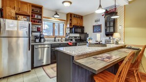A kitchen with wooden cabinets, stainless steel appliances, a granite countertop, and pendant lighting.