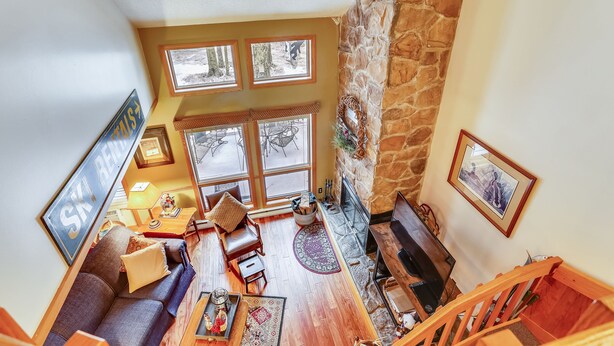 A cozy living room with a stone fireplace, a sofa, a coffee table, and a TV.