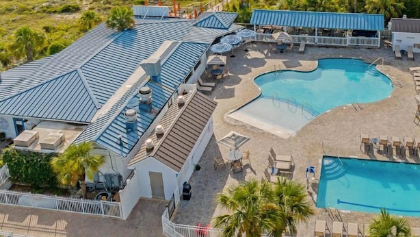 Un resort con una piscina grande, acceso a la playa y vistas al océano.