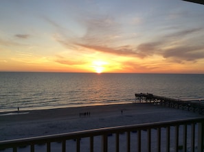 A sunset over the ocean with a pier extending into the water.