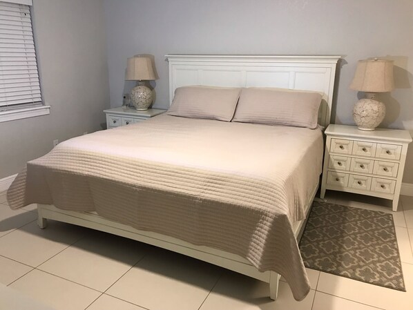 A bedroom with a bed, two nightstands, and a rug.