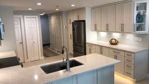 Una cocina moderna con una isla central, electrodomésticos de acero inoxidable y armarios de colores claros.