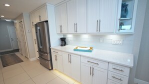 Una cocina moderna con armarios blancos, electrodomésticos de acero inoxidable y una encimera con una cafetera y una caja.
