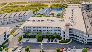 A coastal hotel with multiple buildings, a parking lot, and a beach in the background. - Summer & July 4th Savings at Beachside Colony Tybee's ONLY Oceanfront Resort 3/2 (Tybee Island)