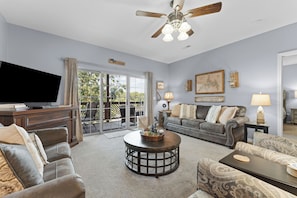 Un salon équipé d’une télévision, d’un ventilateur de plafond, d’une cheminée et offrant une vue sur l’extérieur.