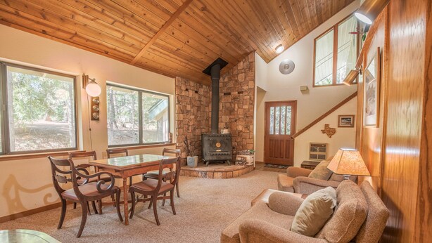 Una sala de estar acogedora con chimenea de piedra, techo de madera y ventanas amplias.