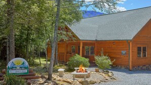 A log cabin with a stone fire pit and a sign indicating 'Maranville' and 'Amet Way'. - Live, Laugh, Love Pool Lodge: Indoor Pool, Theater (Cosby)
