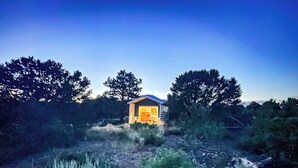 A small, single-story building with a sloped roof, surrounded by dense vegetation and trees. - W-W: Pavilion and Glamping Village (Monticello)