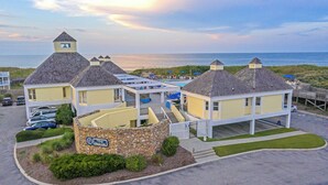 Un hotel costero con varias construcciones, un muro de piedra y vistas a la playa.