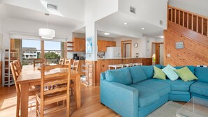 Un salón espacioso con una mesa de comedor de madera, un sofá azul y una cocina al fondo.