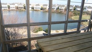 Eine Holzterrasse mit einer Bank mit Blick auf einen See und Wohnhäuser.