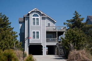 A two-story building with a garage, a balcony, and a small porch. - Wedges 7: Pet-Friendly | Shared Pool & Pickleball (Nags Head)