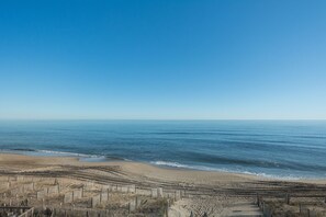 A beach with a wooden fence and a clear view of the ocean.