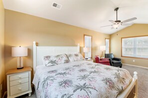 A bedroom with a bed, nightstands, a chair, and a ceiling fan.