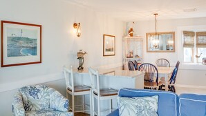 Ein Essbereich mit einem weißen Tisch und Stühlen, einer Chandelüster und einem gerahmten Bild an der Wand.